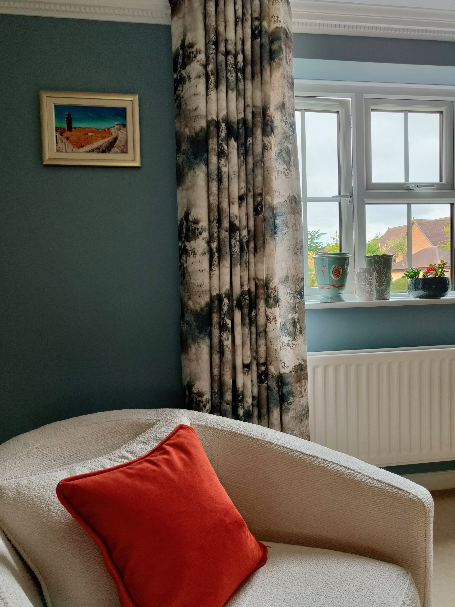 Abstract curtains in blue living room with cream chair